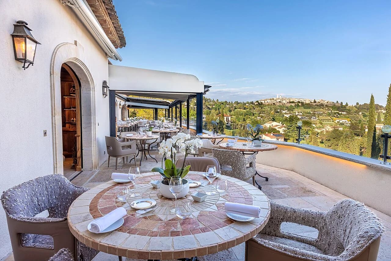 A laid table on the terrace of Alain Llorca’s dining room, facing the hilltop village of Saint-Paul-de-Vence