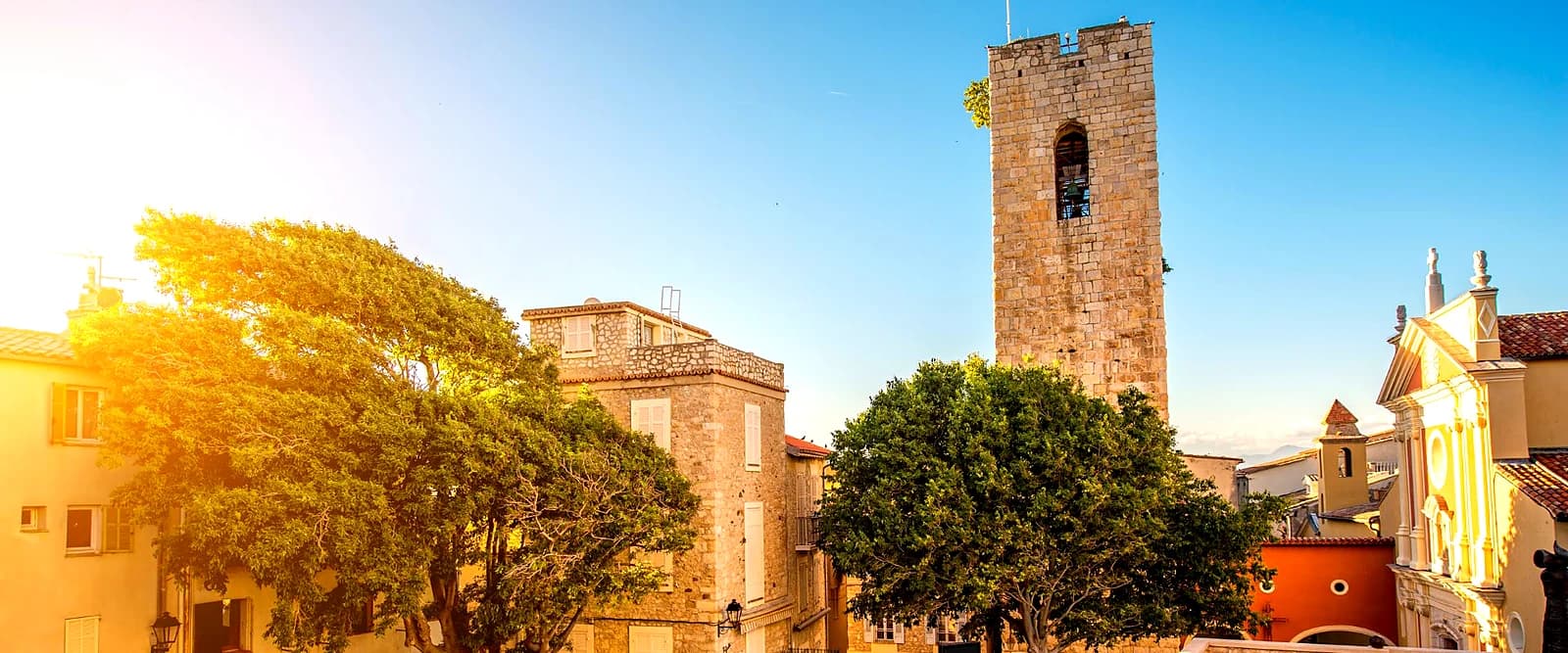 The cathedral bell tower next to the Château Grimaldi, backlit by the late sun