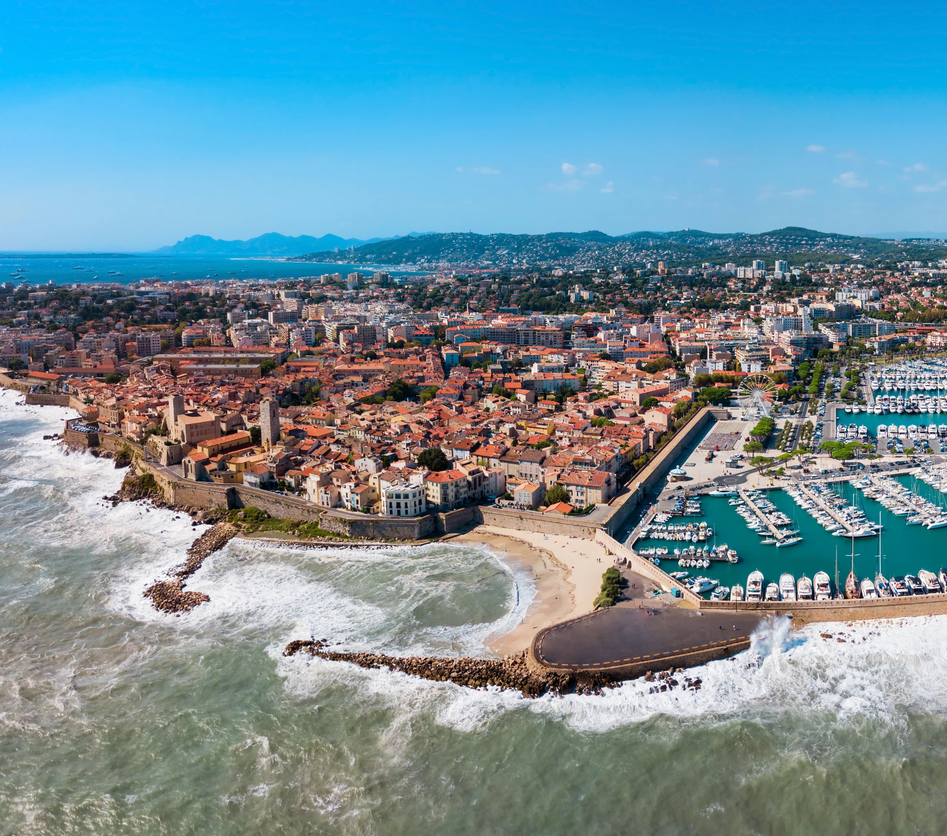 Aerial view of Old Antibes inside its seafront ramparts, the cathedral bell tower and the Grimaldi castle above La Gravette beach