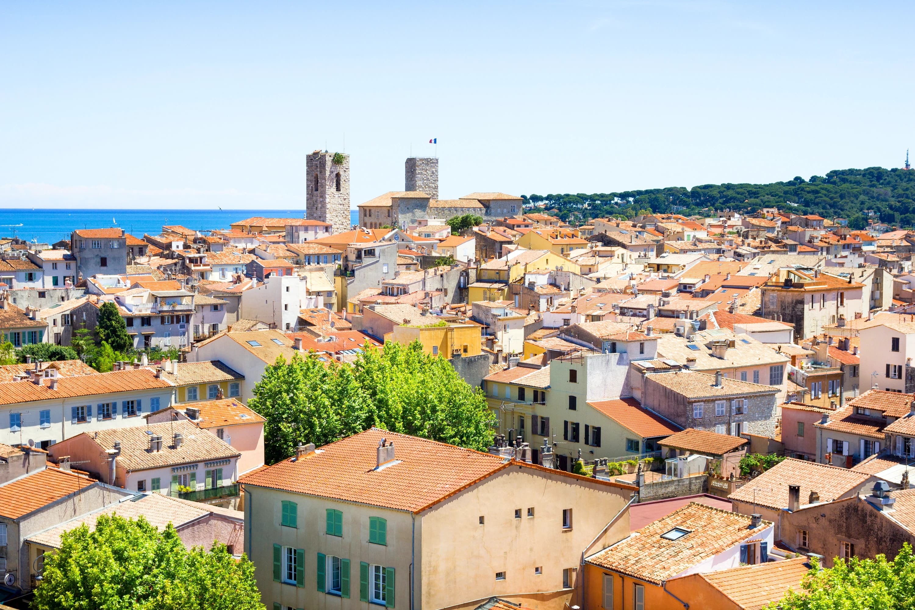 The tiled rooftops of Old Antibes, the cathedral bell tower and the Grimaldi castle tower above the Mediterranean