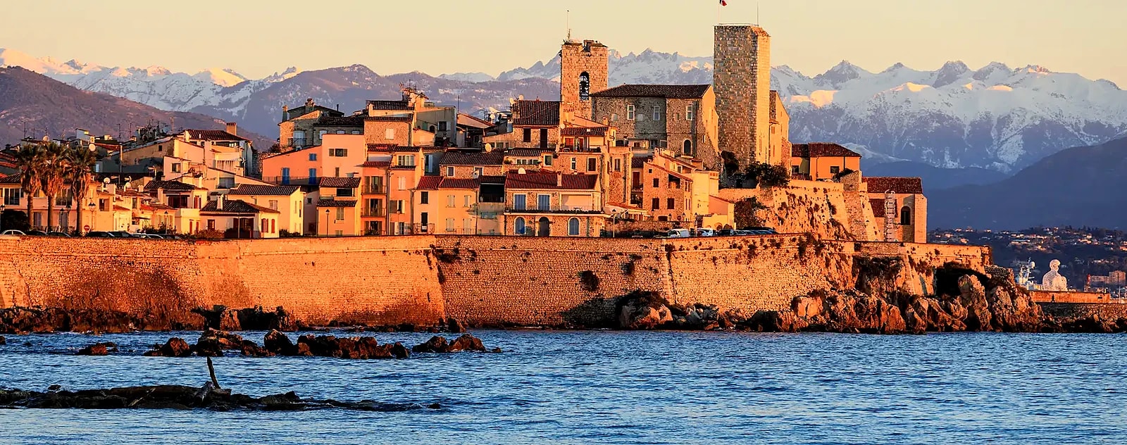 Winter sunset on the ramparts of Old Antibes, the snow-covered Alps across the bay