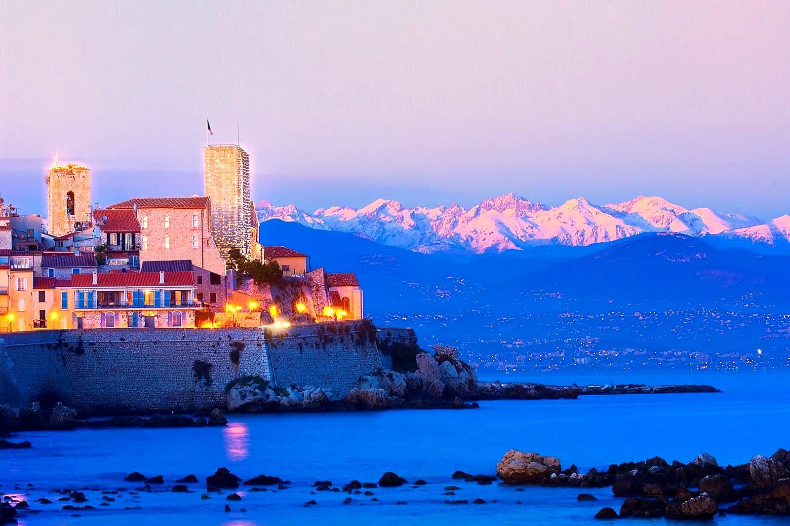 Old Antibes at winter dusk, the château lit above the sea and the snow-capped Alps turning pink behind