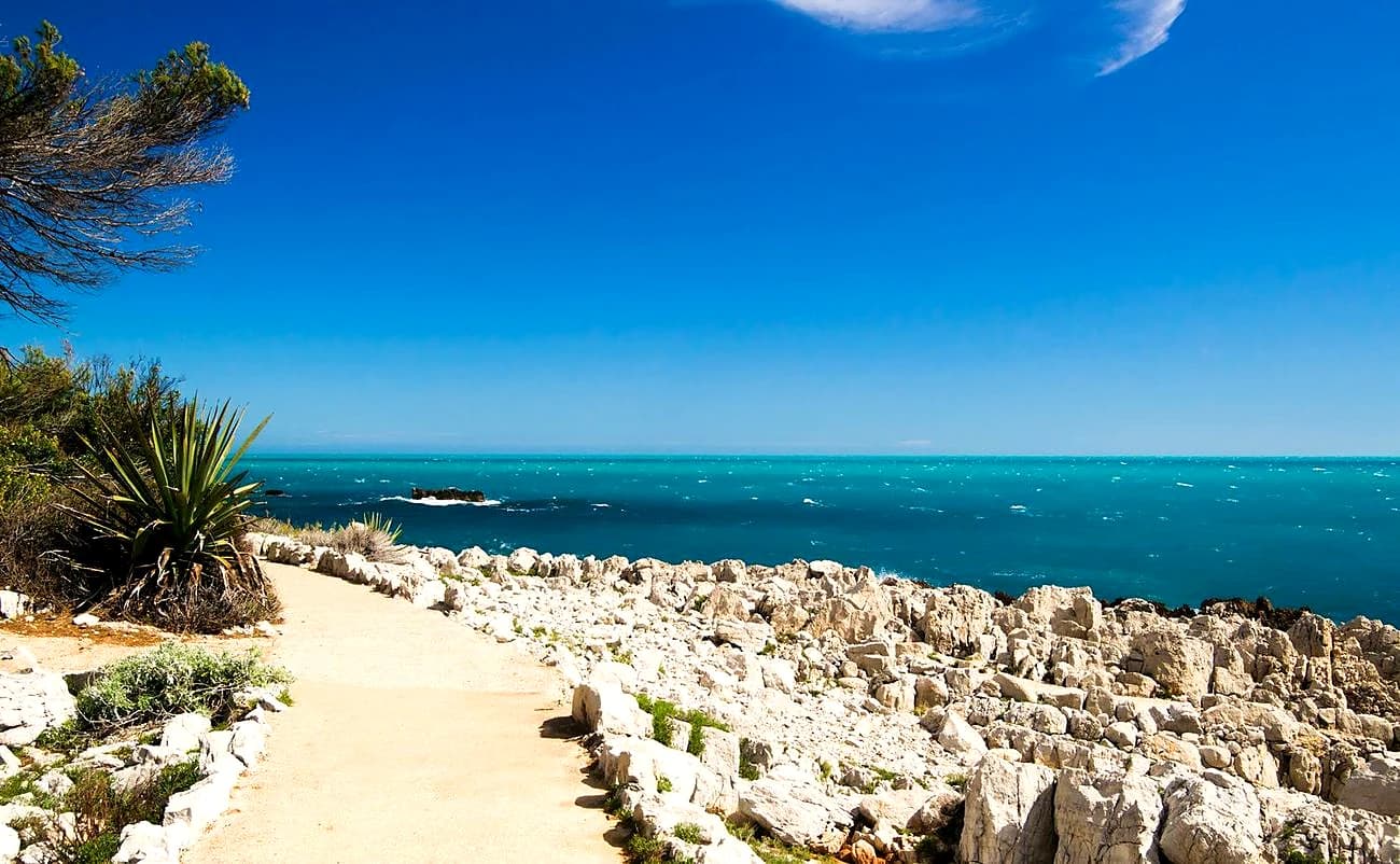 The waymarked coastal path of the Cap d’Antibes running over white limestone beside turquoise water