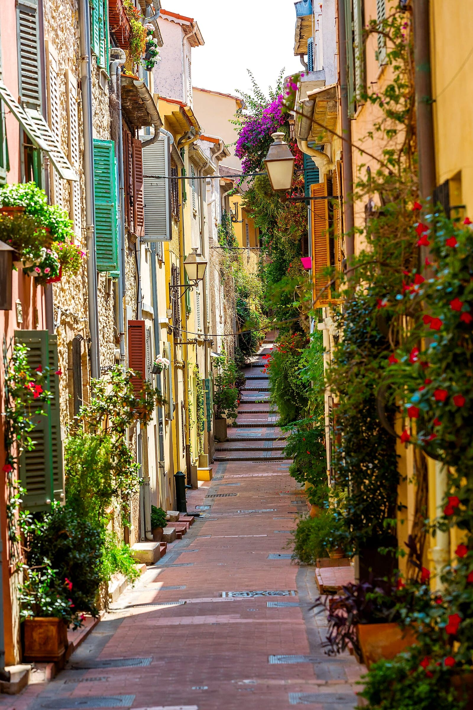 Une ruelle du vieil Antibes avec une valise, ou l’arrivée à pied depuis le parking — illustre que la voiture s’arrête au